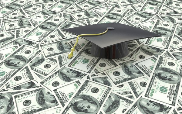 Graduation cap sitting atop a large pile of hundred dollar bills.