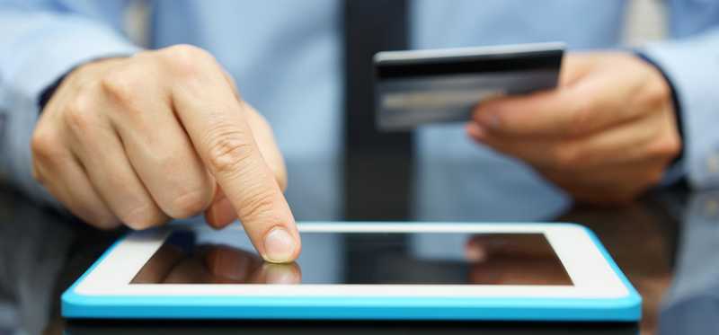 A person making a purchase on a tablet with a credit card.