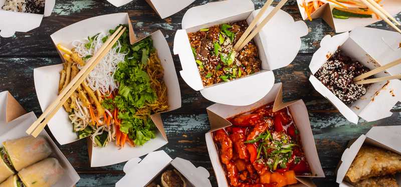 Takeout boxes full of various foods.