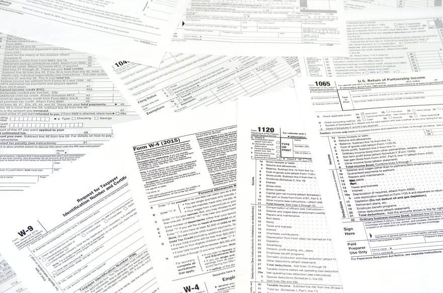 A pile of scattered tax forms that includes a W-9 and W-4.
