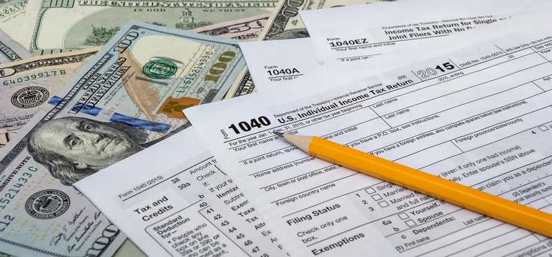 Tax return forms with money and a pencil.