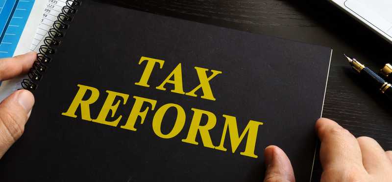 Man's hands holding a tax reform notebook.