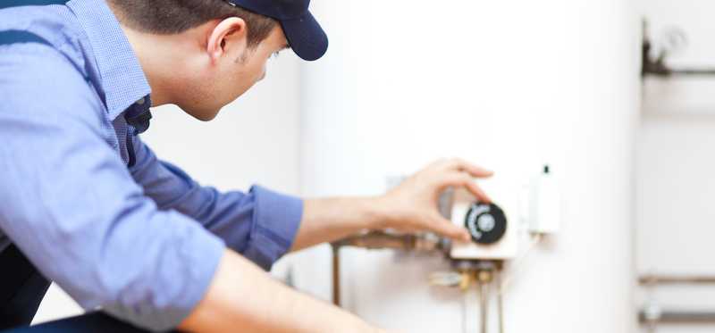 A technician adjusting dial on a water heater.
