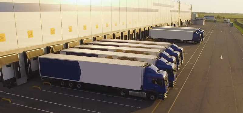 Tractor trailers being loaded behind a warehouse.