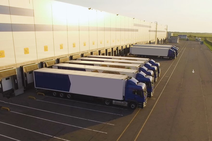 Tractor trailers being loaded behind a warehouse.