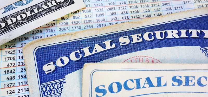 Two Social Security cards and two hundred dollar bills partially covering a benefit calculations card.