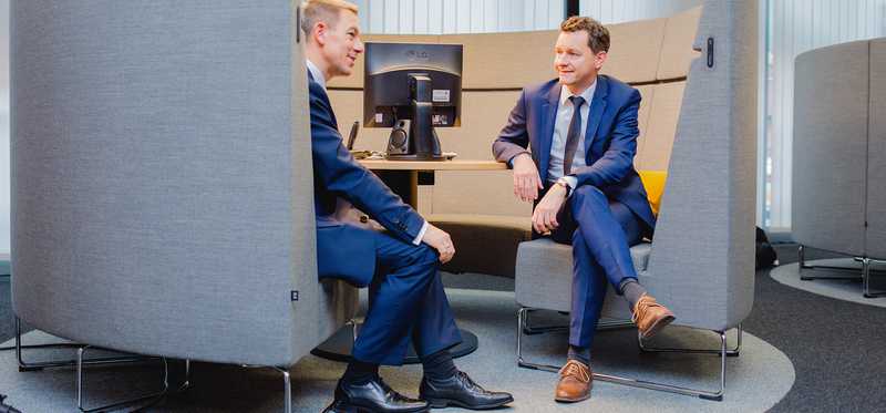 Two businessmen having a discussion inside a bank branch