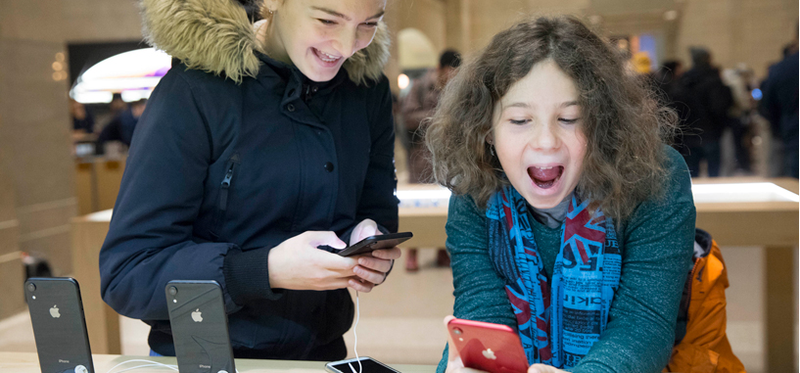 Two children playing with new iPhones in an Apple store
