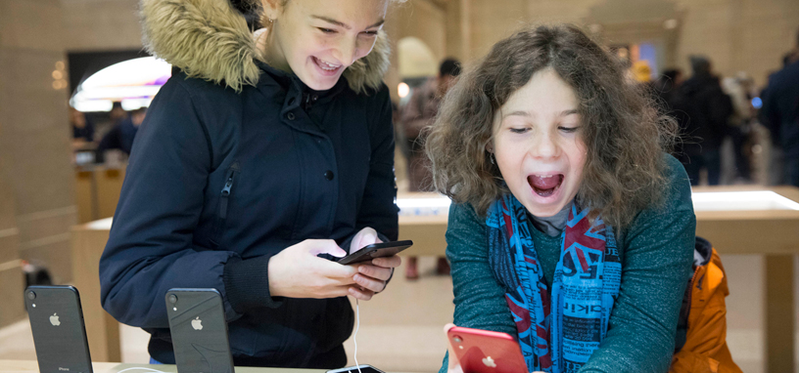Two children playing with new iPhones in an Apple store
