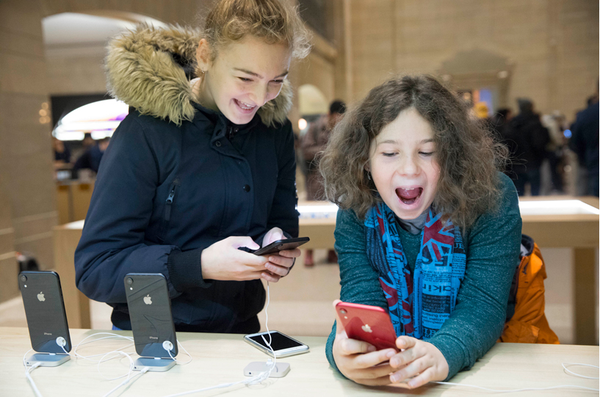 Two children playing with new iPhones in an Apple store