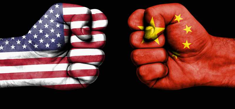 Two fists, one colored as the American flag, and one colored as the Chinese flag, squaring off.