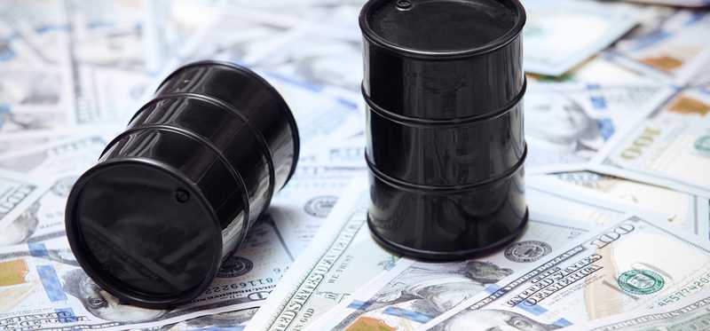 Two oil barrels on top of U.S. currency.