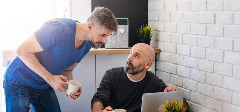 Two people discussing something on laptop screen.