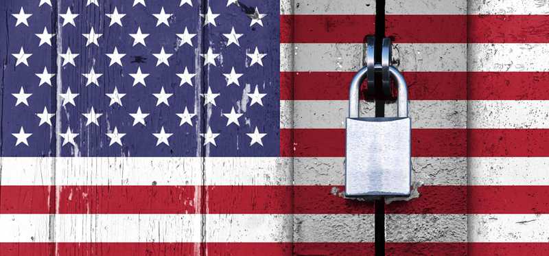 United States American trade embargo represented by U.S. flag on a wooden door locked with a padlock.