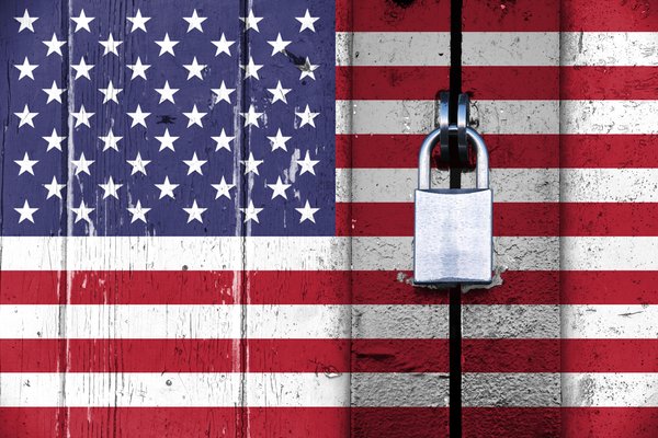 United States American trade embargo represented by U.S. flag on a wooden door locked with a padlock.