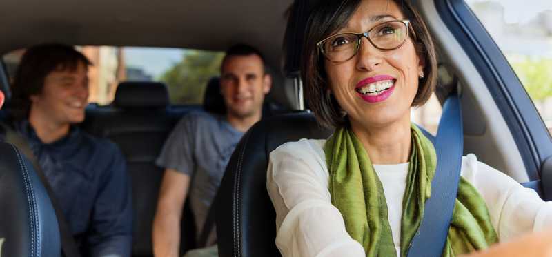 A driver glances in the rearview mirror at passengers.