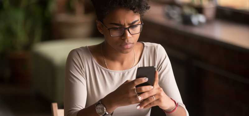 Frustrated woman looking at her phone screen.