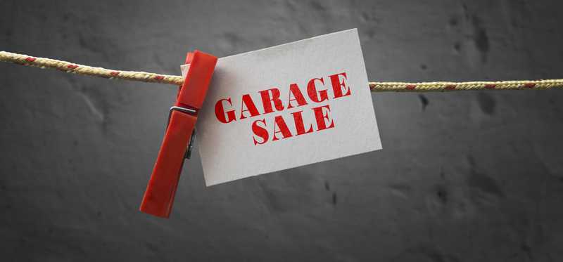 A sign for a garage sale is clipped to a line with a clothespin