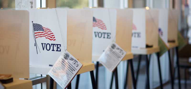 Voting booths with pamphlets separated by small partitions.