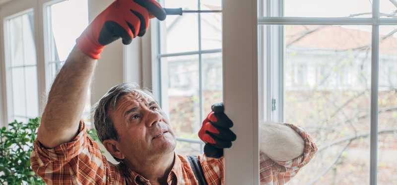 A person using a screwdriver to adjust a French door.