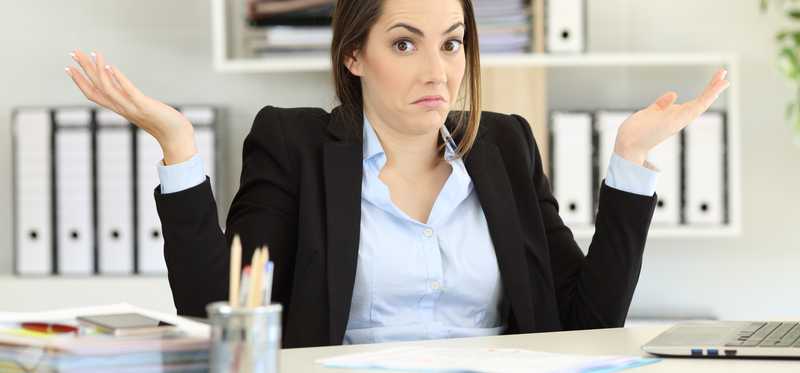 Woman in business suit shrugging at desk