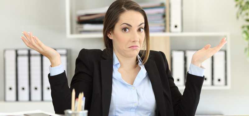 Person in business suit is shrugging at desk.