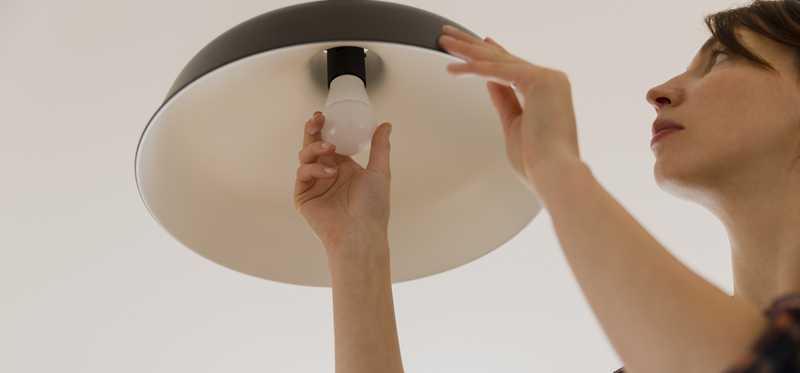 Someone installing an LED lightbulb in a ceiling fixture.