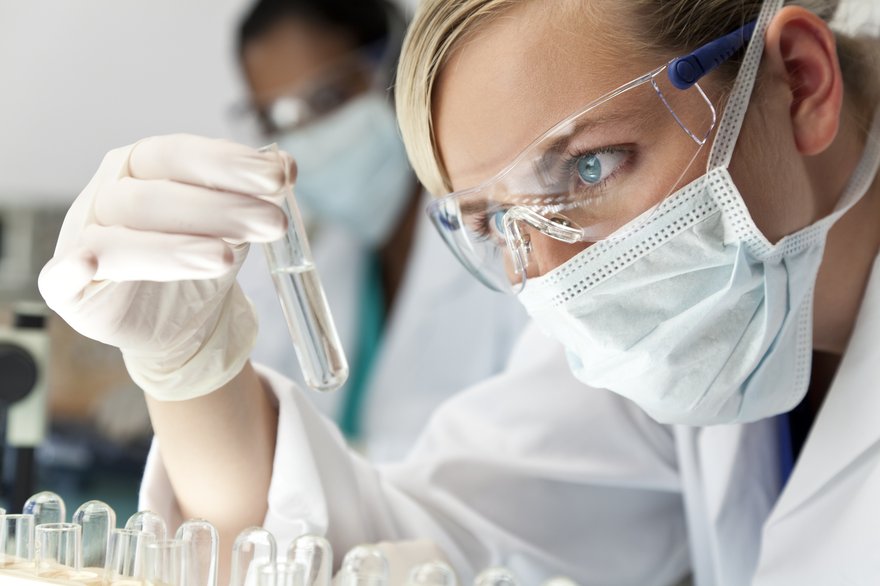 Woman scientist in lab holding up test tube.