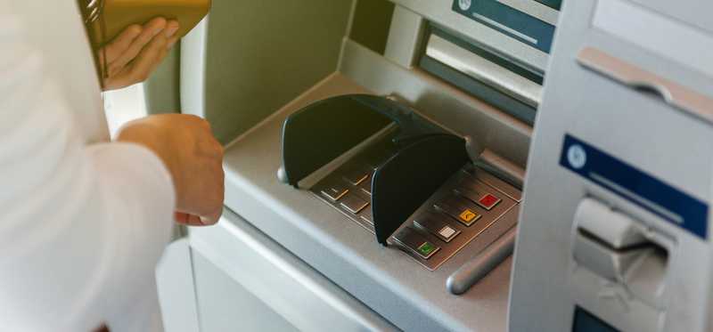 A woman stands at an ATM kiosk.