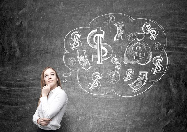Woman stands in front of chalkboard featuring thought bubble with dollar signs.