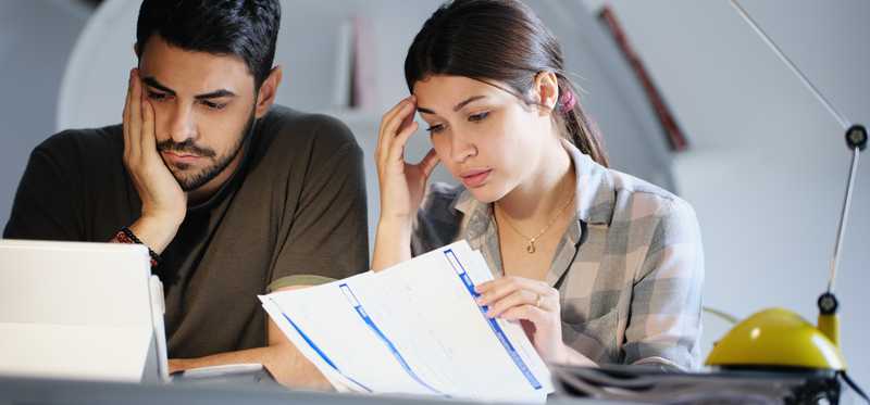 Two people look worried as they review paperwork.