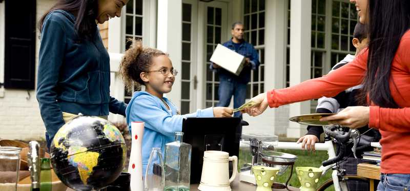 Young girl and mom collecting money from woman at yard sale
