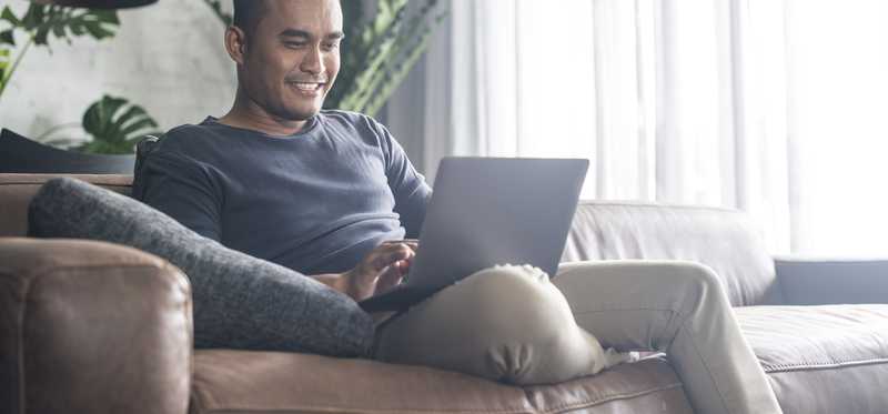 Young man smiling on laptop at home