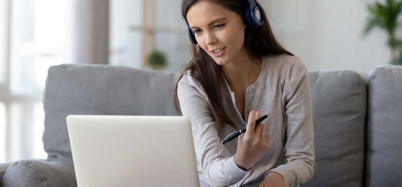 Young woman with headphones speaking into laptop