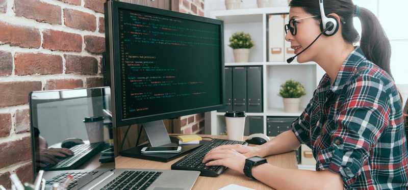 Person with headset is coding on computer.