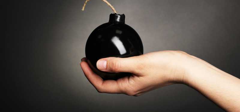 An outstretched palm is holding a bomb with a fuse.