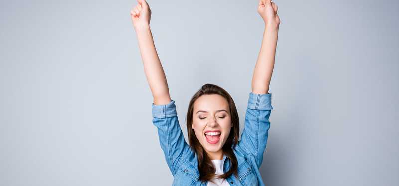 Happy young woman with arms up.