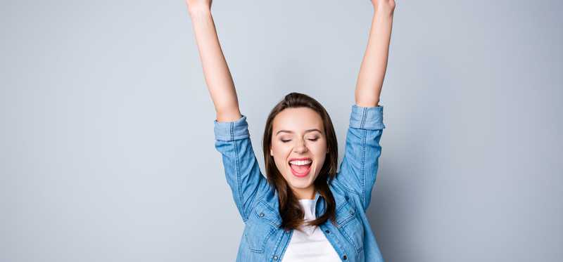 Happy young woman with arms up.