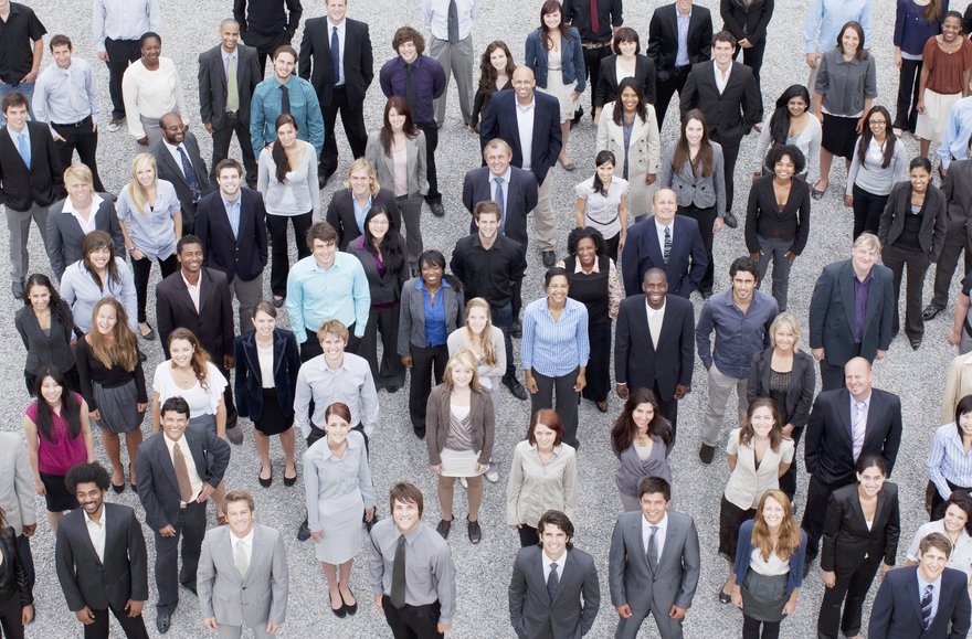 A large diverse crowd of smiling people in business attire.