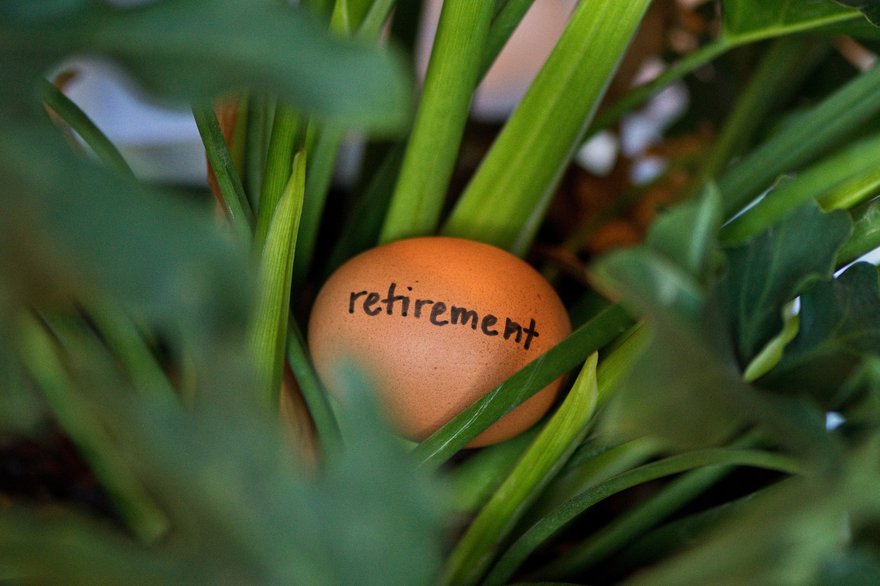 An egg with the word Retirement written on it sitting in a nest.