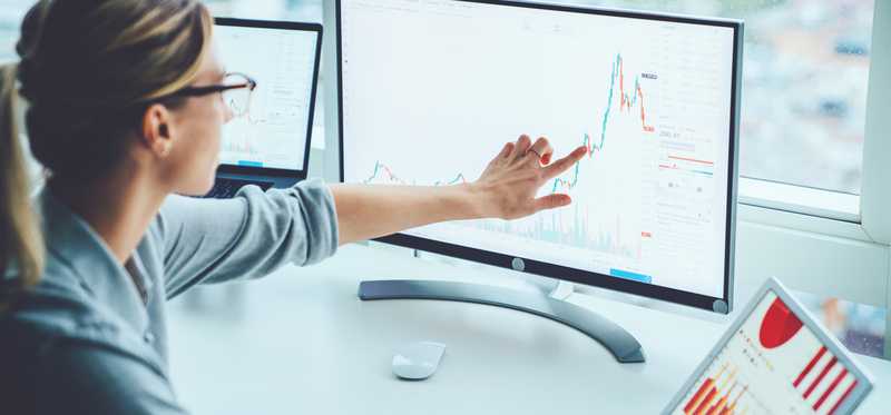 Person points to graph on monitor showing volatility.