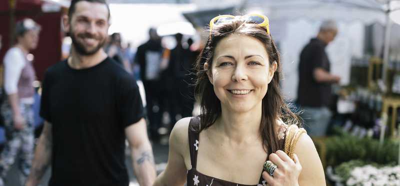 Two people holding hands and walking through outdoor shopping area.