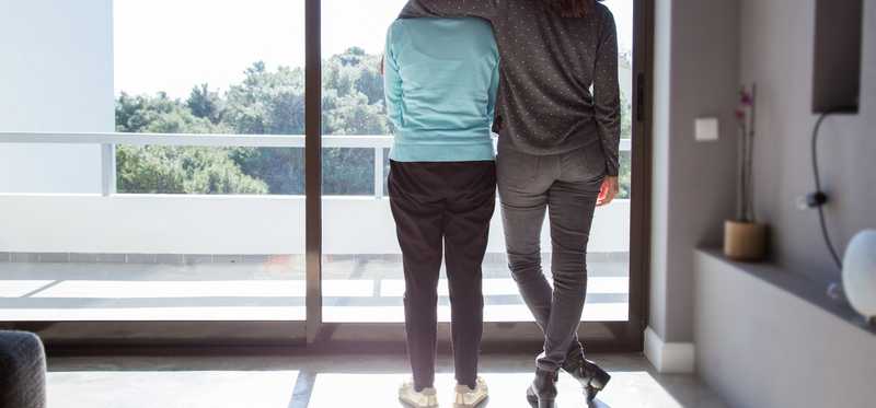 Young person with their arm around an older person.