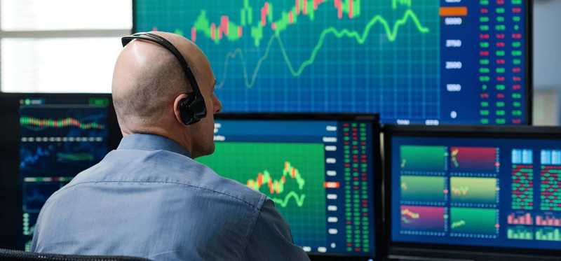 Person viewing charts on multiple monitors.