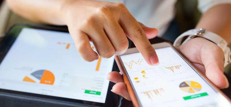 A phone and a tablet are shown with charts on them.