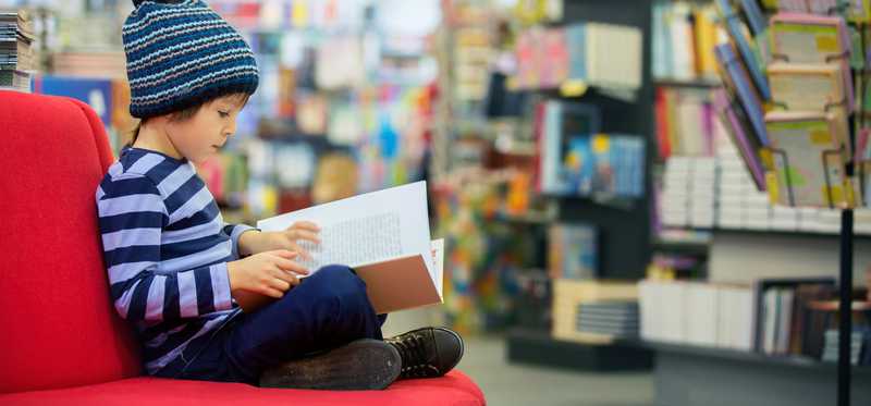 A child reads a book inside a bookstore.