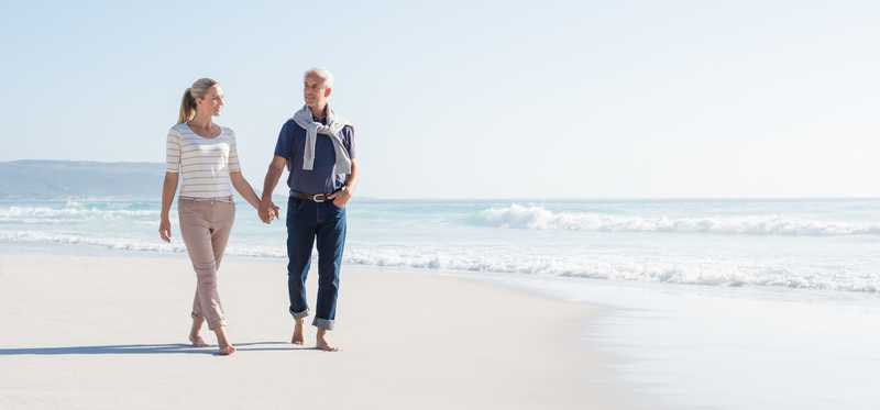 An older couple walks on a beach