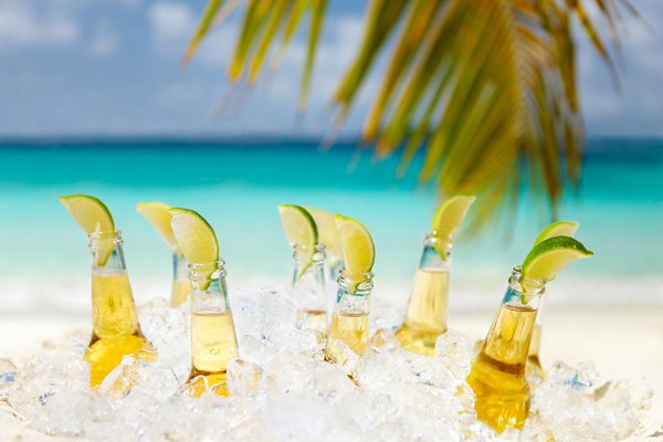 Beers with lime in ice with beach in the background.