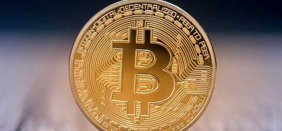 A gold bitcoin standing on its edge.