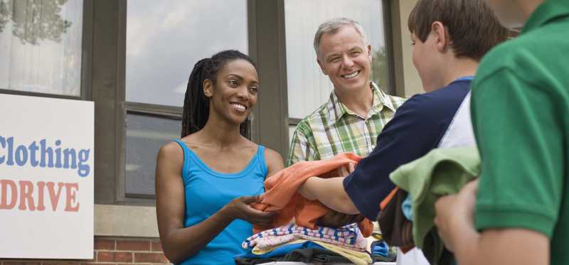 boy handing some clothes to a woman at a clothing donation event